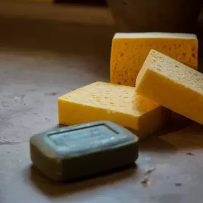 Três blocos de queijo amarelo e barra de sabonete verde sobre superfície rústica