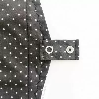 Tecido preto com bolinhas brancas e aba com ilhós metálicos