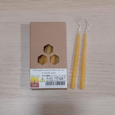 Caixa castanha com velas amarelas de cera de abelha e duas velas ao lado sobre mesa de madeira.