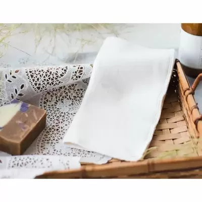 Cesto com toalha branca e sabão marrom sobre forro rendado branco