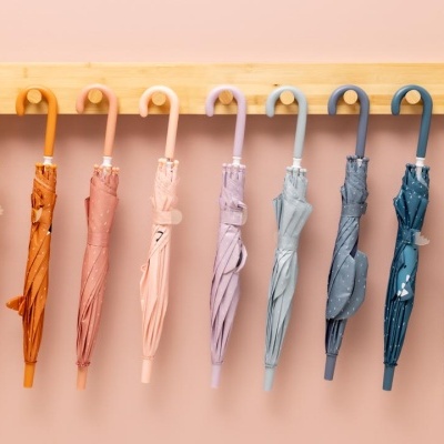 Nove guarda-chuvas coloridos fechados pendurados numa barra de madeira