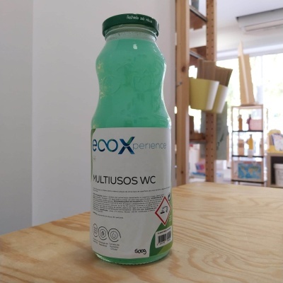 Frasco de limpeza multiusos ecoXperience em vidro com líquido azul esverdeado.