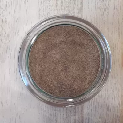 Frasco de vidro com pó castanho visto de cima sobre madeira clara