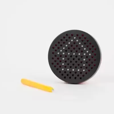 Objeto redondo preto com furos e ferramenta amarela ao lado sobre fundo branco