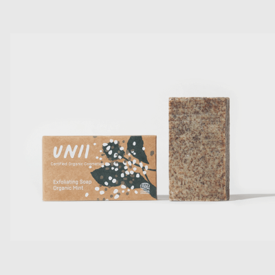 Sabonete esfoliante castanho ao lado da embalagem de papel reciclado com texto e ilustração de folhas