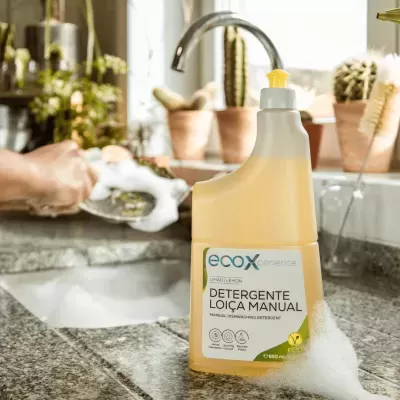 Detergente para loiça manual amarelo numa cozinha com pia e plantas ao fundo