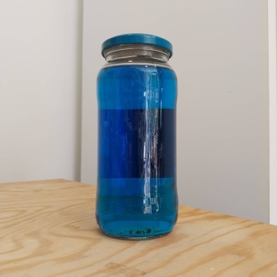 Frasco de vidro com líquido azul em superfície de madeira