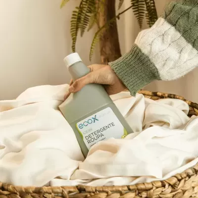 Frasco de detergente para roupa ecox numa cesta com tecido branco