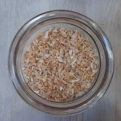 Tigela de vidro com lascas amarelo claro e alaranjadas sobre superfície clara