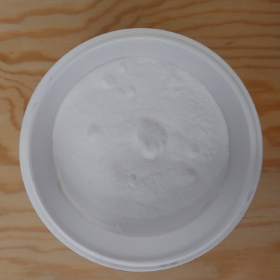 Recipiente branco com pó branco numa superfície de madeira clara