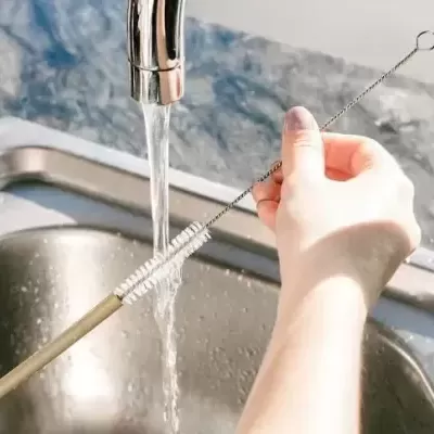 Mesa de cozinha com pia de aço inox e escova limpa canudos com cabo amarelo claro e cerdas brancas