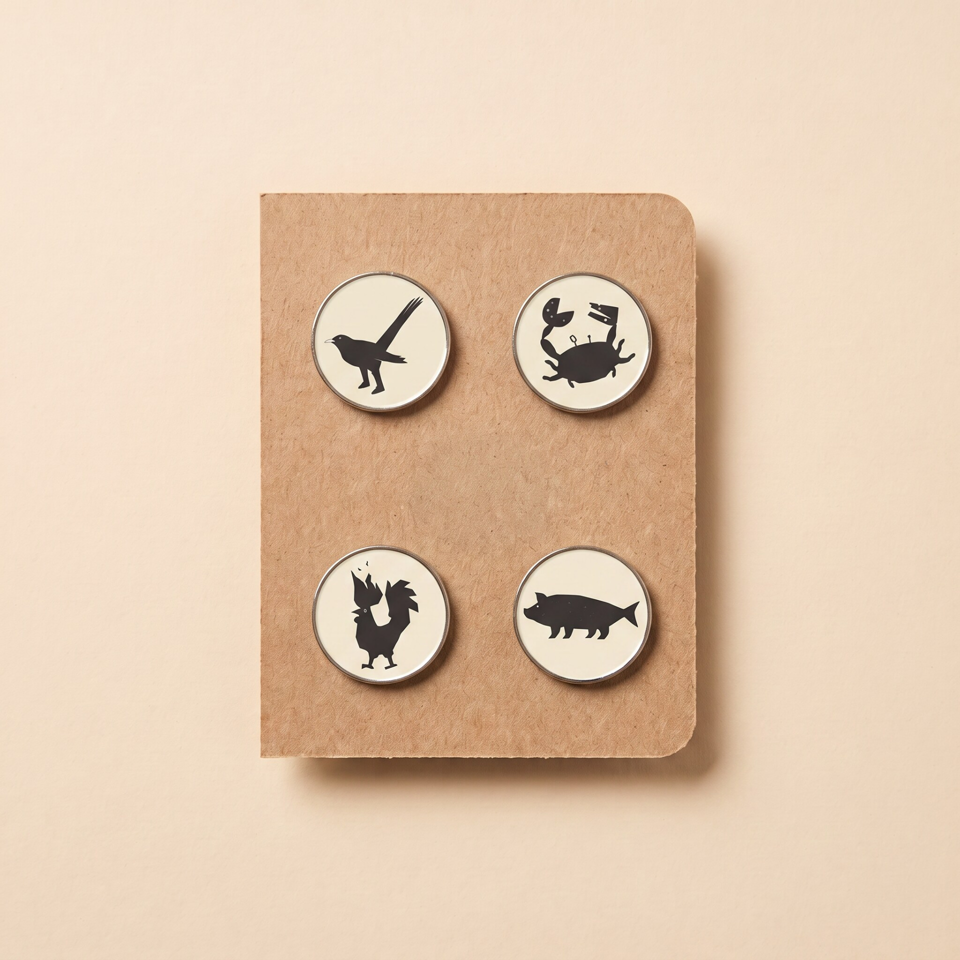 Species pin set Four round pins with black animals silhouettes on white backgrounds on a brown textured card.