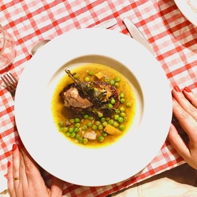 Plate with stew containing peas, potatoes, and meat on checkered tablecloth