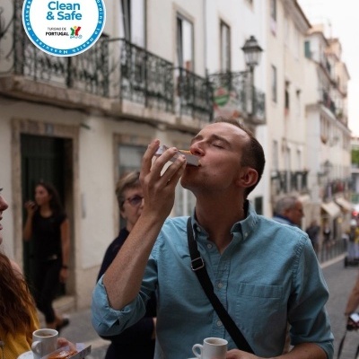 Man enjoying espresso and pastry on street with Portugal Clean & Safe sign