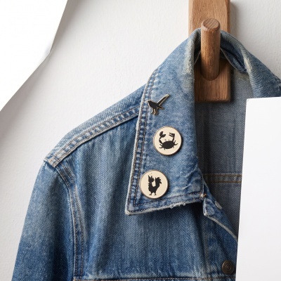 Blue denim jacket with pins hanging on wooden wall hook