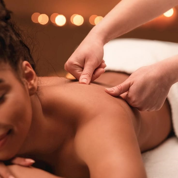 MASSAGEM - Cascais Mulher a receber massagem nas costas num ambiente relaxante com luzes quentes