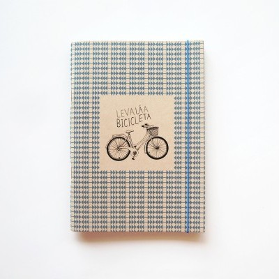 Caderno com capa de tecido azul e branco xadrez e etiqueta com desenho de bicicleta e texto