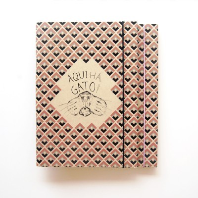 Caderno com padrão geométrico e ilustração de gato com texto AQUI HÁ GATO!