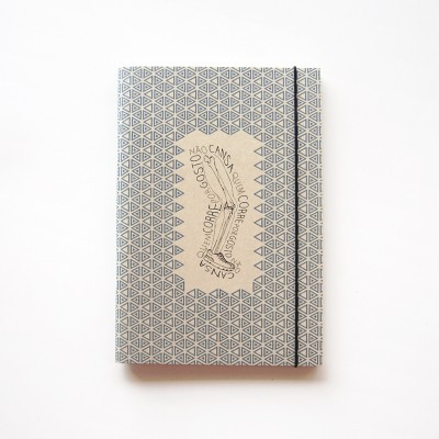 Caderno cinza com padrão geométrico e etiqueta com texto e desenho de pé