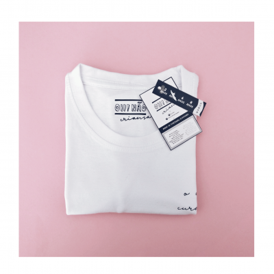 T-shirt branca dobrada com etiquetas em fundo rosa