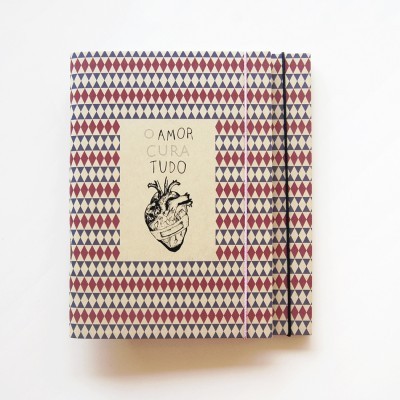 Caderno com padrão geométrico e texto 'O AMOR CURA TUDO' na capa