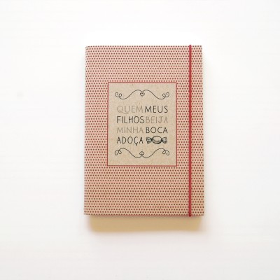 Caderno com capa bege com pontos vermelhos e elástico vermelho
