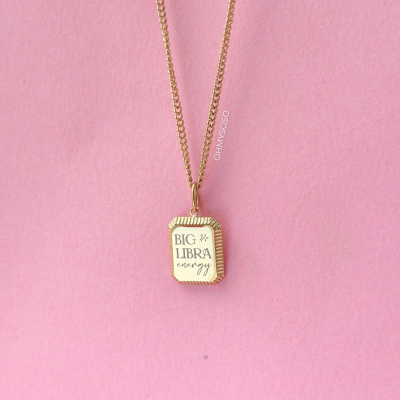 Colar dourado com pendente retangular e texto BIG LIBRA energy