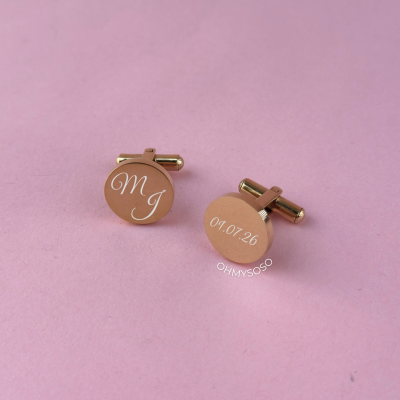 Par de botões de punho dourados com inscrições em branco sobre fundo rosa claro.