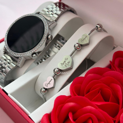 Conjunto de relógio prateado e pulseira com corações gravados numa caixa com rosas vermelhas.