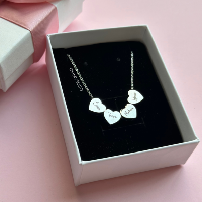Colar com pendentes em forma de coração dentro de caixa branca com interior preto e fundo rosa