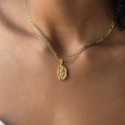 Colar dourado com pendente floral usado no pescoço