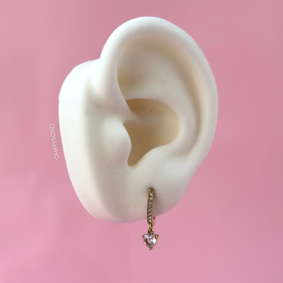Orelha artificial branca com brinco dourado em fundo cor-de-rosa