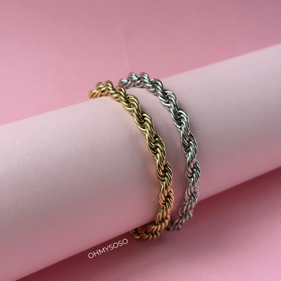 Braceletes trançados dourado e prateado sobre cilindro cor-de-rosa