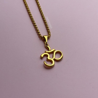 Colar dourado com pendente símbolo Om sobre fundo rosa