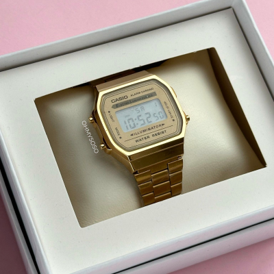 Relógio digital Casio dourado em caixa branca sobre fundo rosa