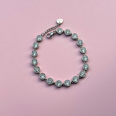 Pulseira prateada com pedras redondas brilhantes sobre fundo rosa