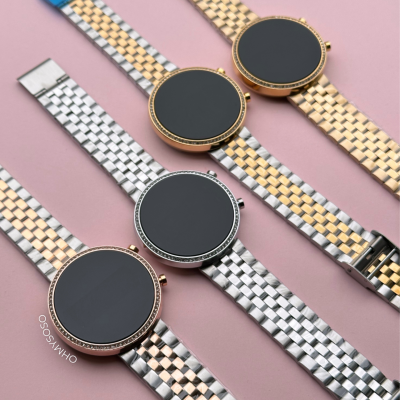 Relógios inteligentes prateados e dourados com mostradores redondos pretos sobre fundo rosa