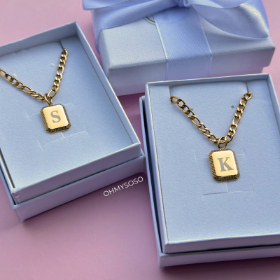 Colares dourados com pendentes de letras em caixas e laço azul