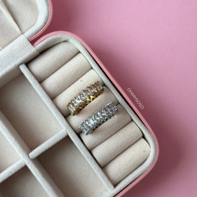 Duas alianças com pedras em caixa de joias sobre fundo rosa