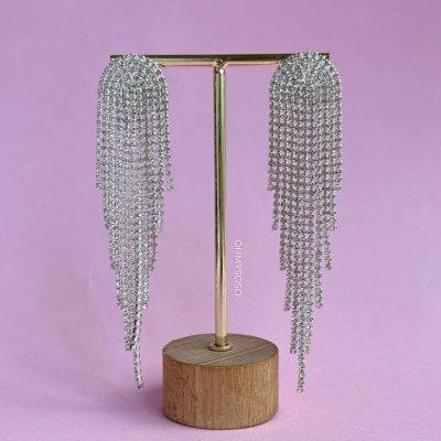 Brincos prateados com correntes de cristais num suporte dourado com base de madeira
