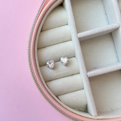 Brincos de coração com pedras transparentes numa caixa de veludo rosa claro