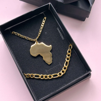 Colar e pulseira dourados com pendente em forma do mapa de África numa caixa preta.
