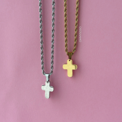 Duas correntes com cruzes, uma prateada e outra dourada, sobre fundo rosa com texto OH MY GOSO