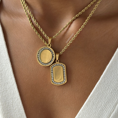 Colares dourados com pendentes cravejados em pele castanha e camisola branca com decote em V