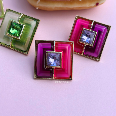 Brincos quadrados coloridos com pedras brilhantes e doce com glacê rosa em fundo rosa