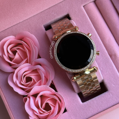 Relógio de pulso dourado e preto numa caixa rosa com flores cor-de-rosa