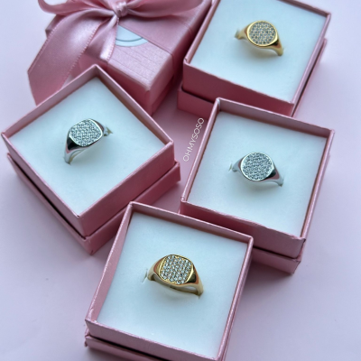 Conjunto de quatro anéis brilhantes em caixas cor de rosa com laço