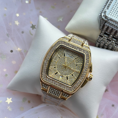 Relógio dourado com pedras brilhantes sobre almofada branca