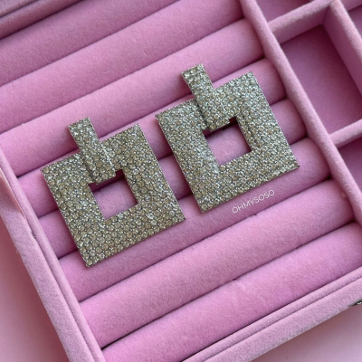 Brincos quadrados prateados com pedras numa caixa de veludo rosa