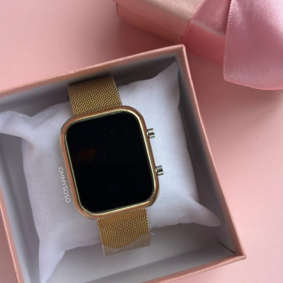 Relógio dourado com mostrador preto em caixa de presente rosa com fita